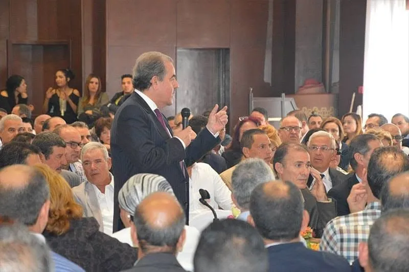 Mondher Zenaidi, microphone in hand, standing and addressing a packed hall